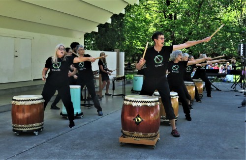 Two rows or drummers standing on a stage performing